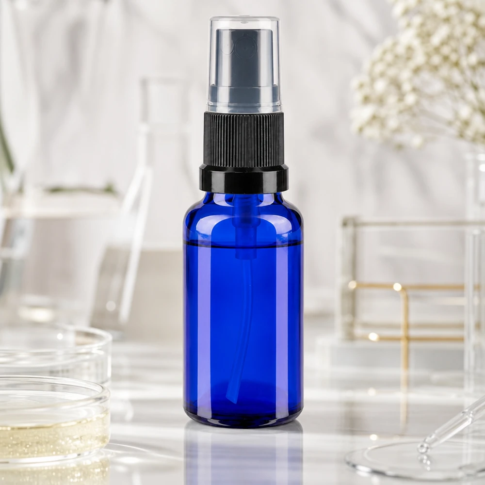 Apotekerflaske blå 20 ml spraytilbehør sort Blå 20 ml laboratoriesprayflaske med sort forstøver på hvid marmorbaggrund