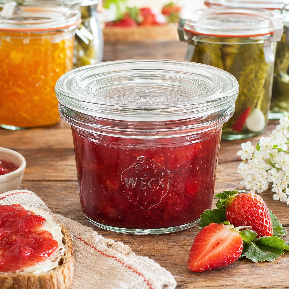 35 ml Briller med glaslåg WECK RR40 WECK 35 ml RR40-krukke fyldt med rød jordbærmarmelade ved siden af friske jordbær og marmeladebrød
