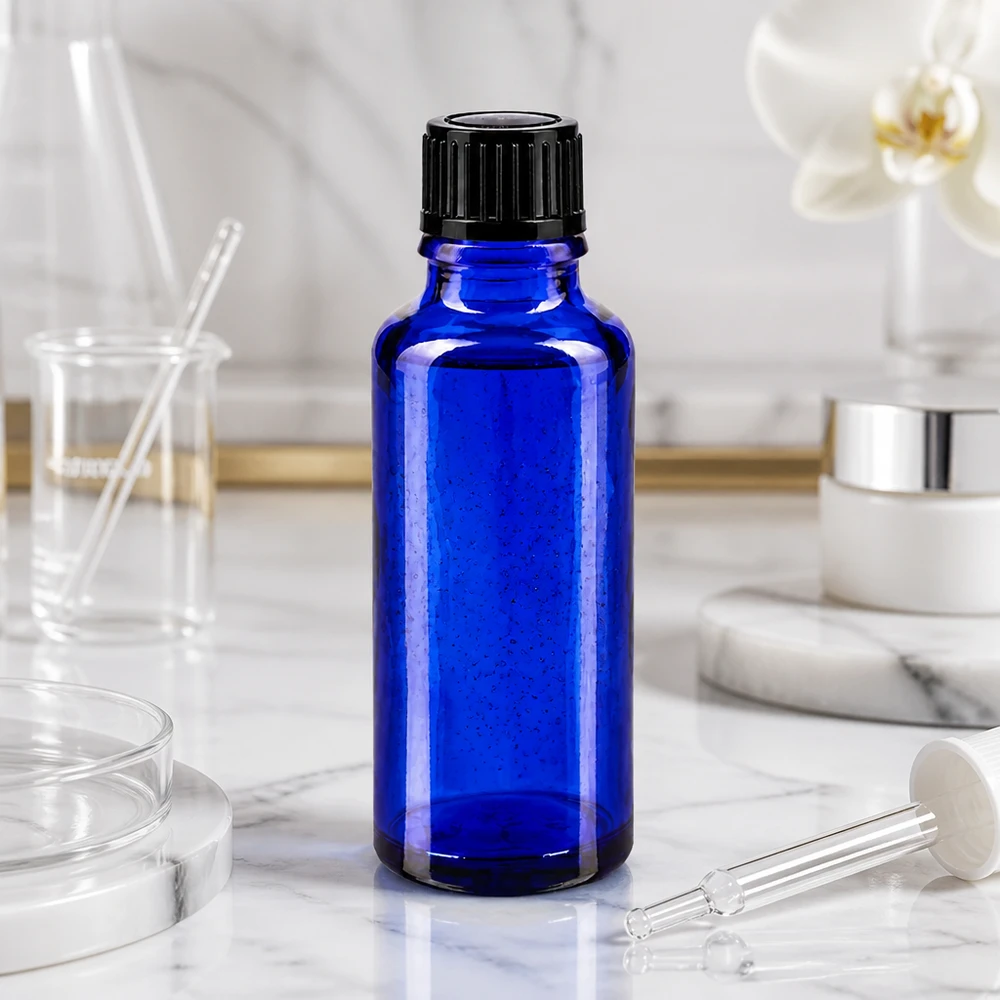 Koboltblå 30 ml glasflaske med sort skruelåg på hvid marmor