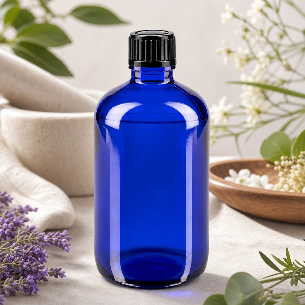 Blå glasflaske på 100 ml med skruelåg, omgivet af lavendel og hvide blomster