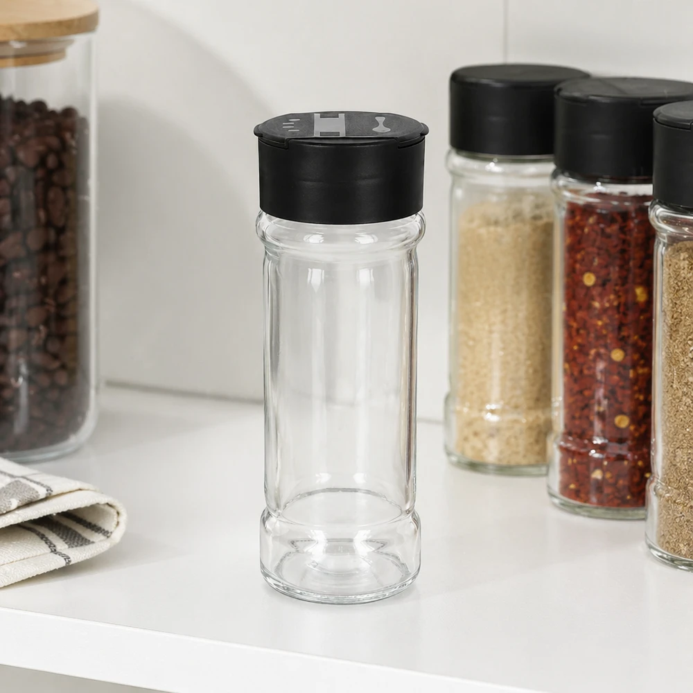 Salt-/krydderikrukke 100 ml med dobbelt strøer, sort Cylindrisk krydderiglas på 100 ml med sort dobbeltstøver ved siden af chiliflager og sesam