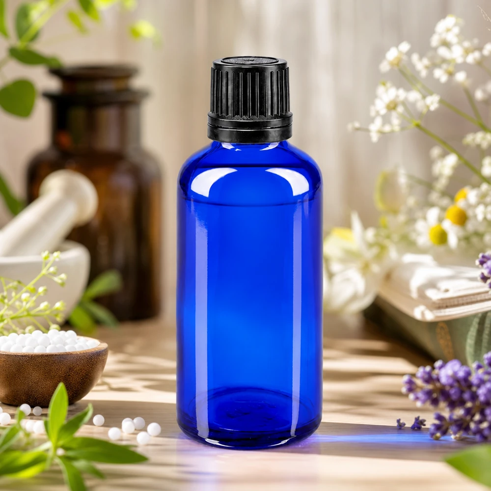 Apoteksflaske blå 50ml skruelåg sort hældeprop r. OV Blå 50 ml apotekerflaske med sort originalprop omgivet af lavendel og kamilleblomster
