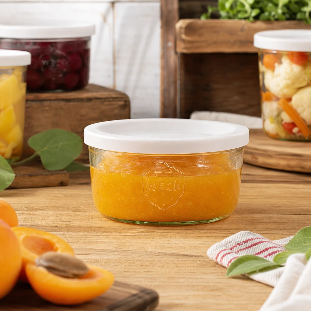 165 ml Briller med friskhedslåg WECK RR80 WECK 165 ml murerbalje fyldt med appelsinmarmelade i et naturligt køkkenmiljø med syltetøjsglas i baggrunden