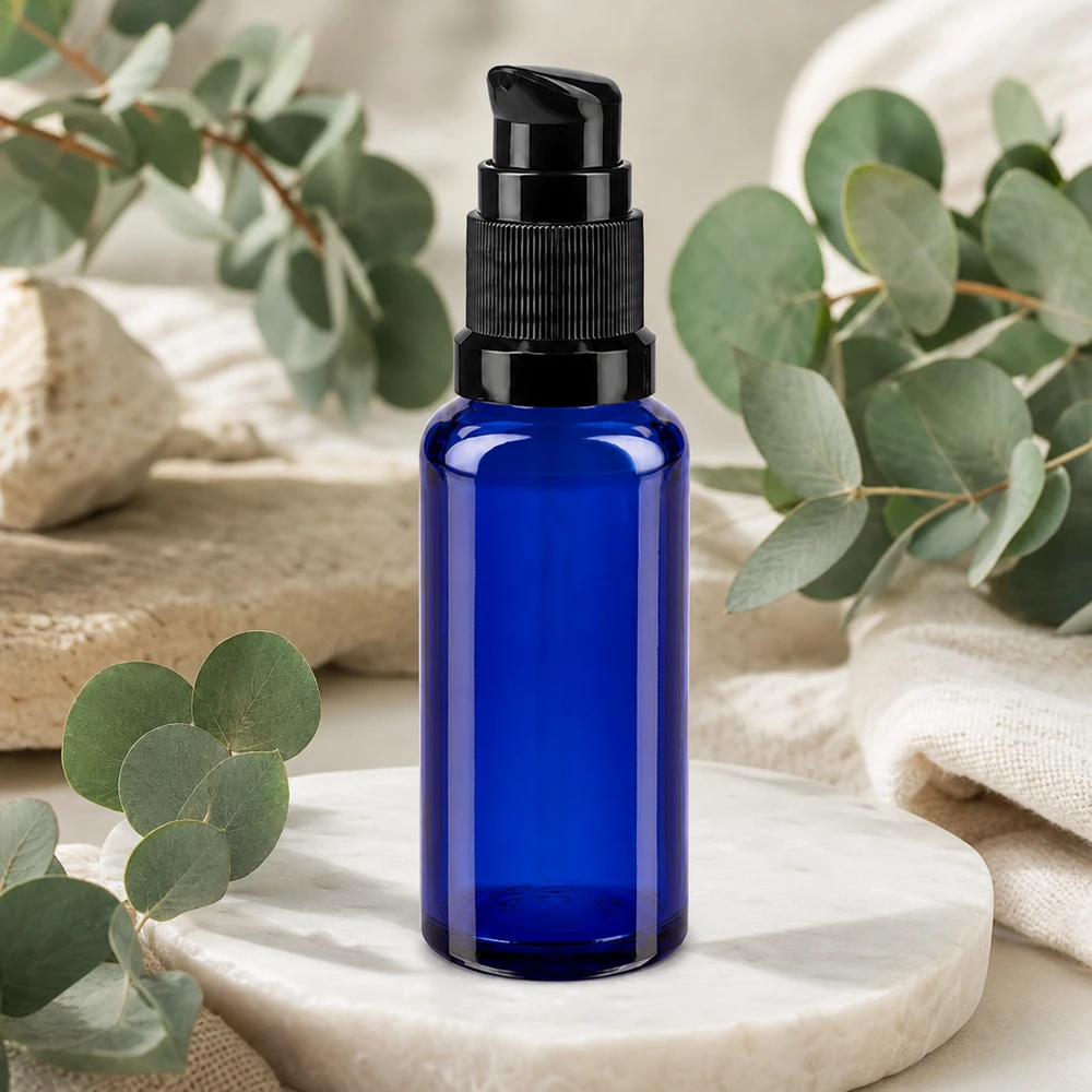 Blå 30 ml pumpeflaske af apotekerglas med sort doseringshoved på marmorsten