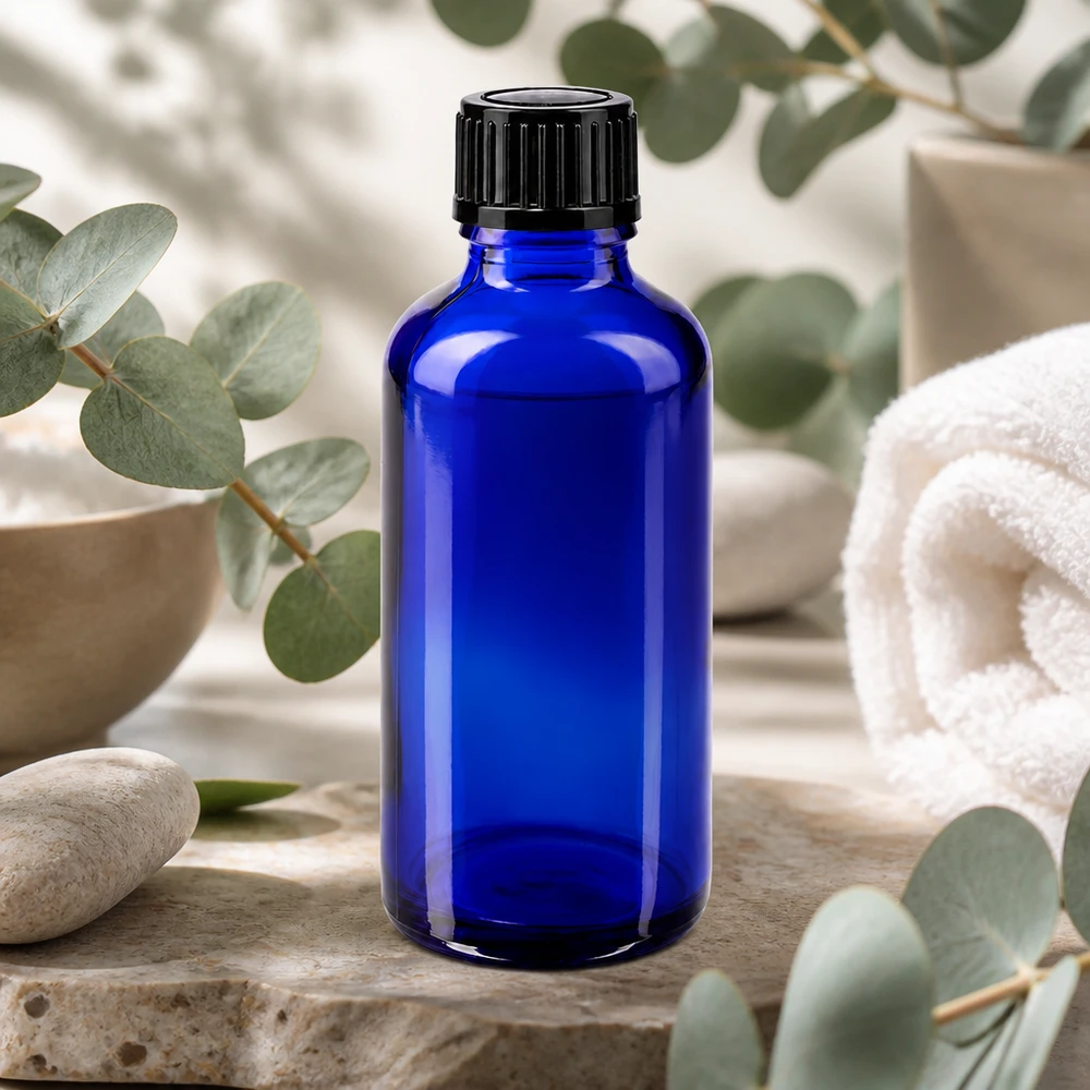 Blå 50 ml apotekerflaske af glas med sort skruelåg på natursten med eukalyptus