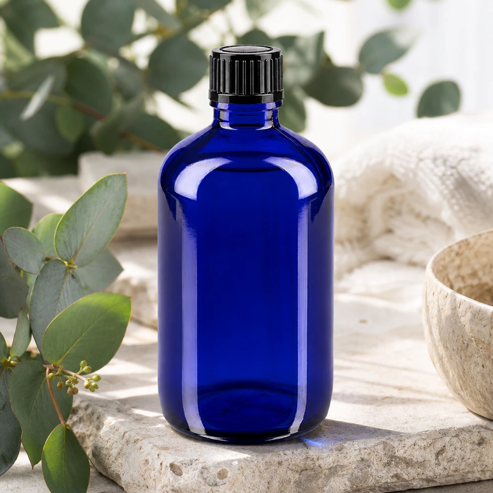 Apoteksflaske blå 100ml skruelåg sort pc Blå 100 ml apotekerflaske med sort standardlukning på natursten med eukalyptus