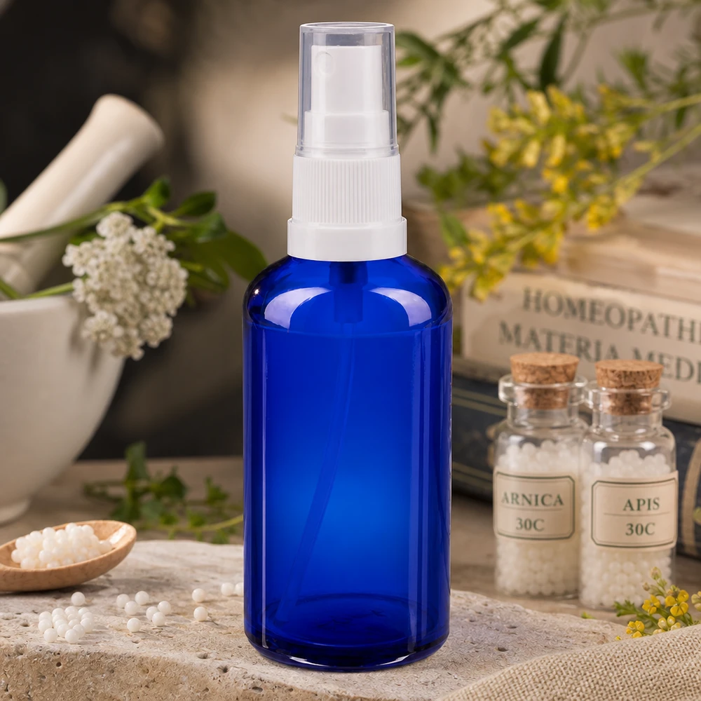 Apoteksflaske blå 50 ml spraytop hvid 50 ml blå apotekersprayflaske af glas med hvidt pumpehoved ved siden af homøopatiske globuli